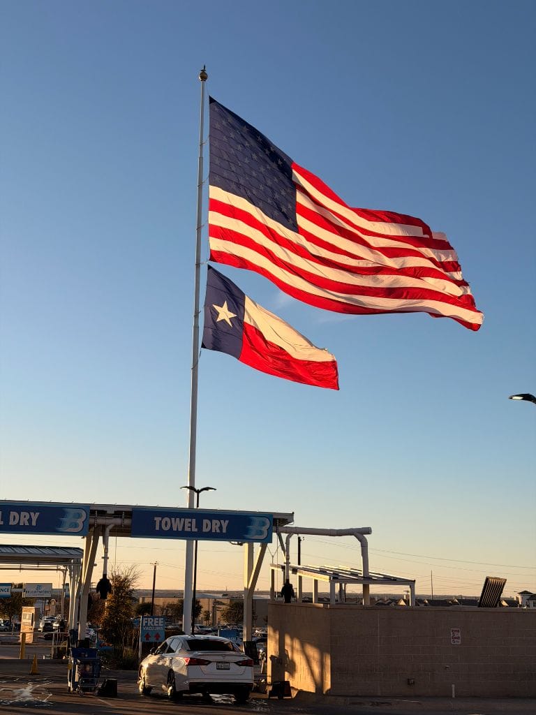 American and Texas flags flying proudly over the Brightworks Fort Worth towel-dry station at golden hour