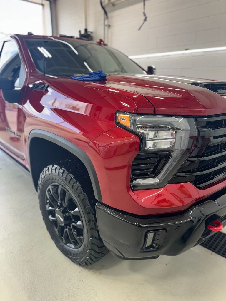 Gleaming red Chevy Silverado 2500 HD ZR2 front end after a full detail at Brightworks Fort Worth — microfiber cloth resting on the hood