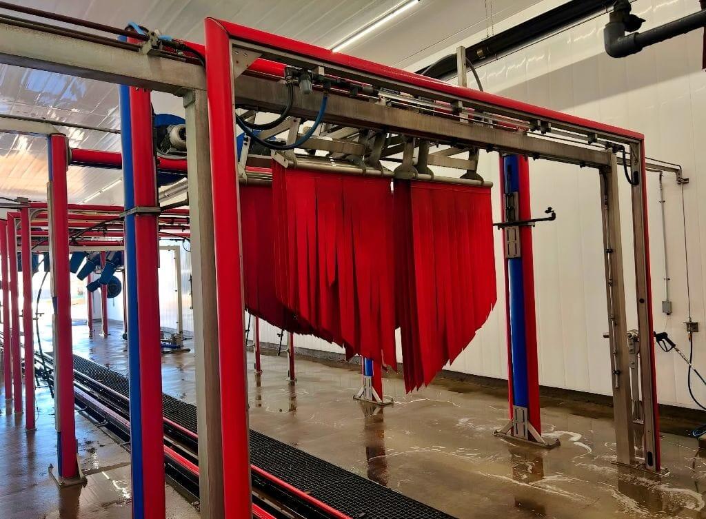 Brightworks Fort Worth exterior wash — red soft-cloth curtain strips hanging from the gantry ready for the next vehicle