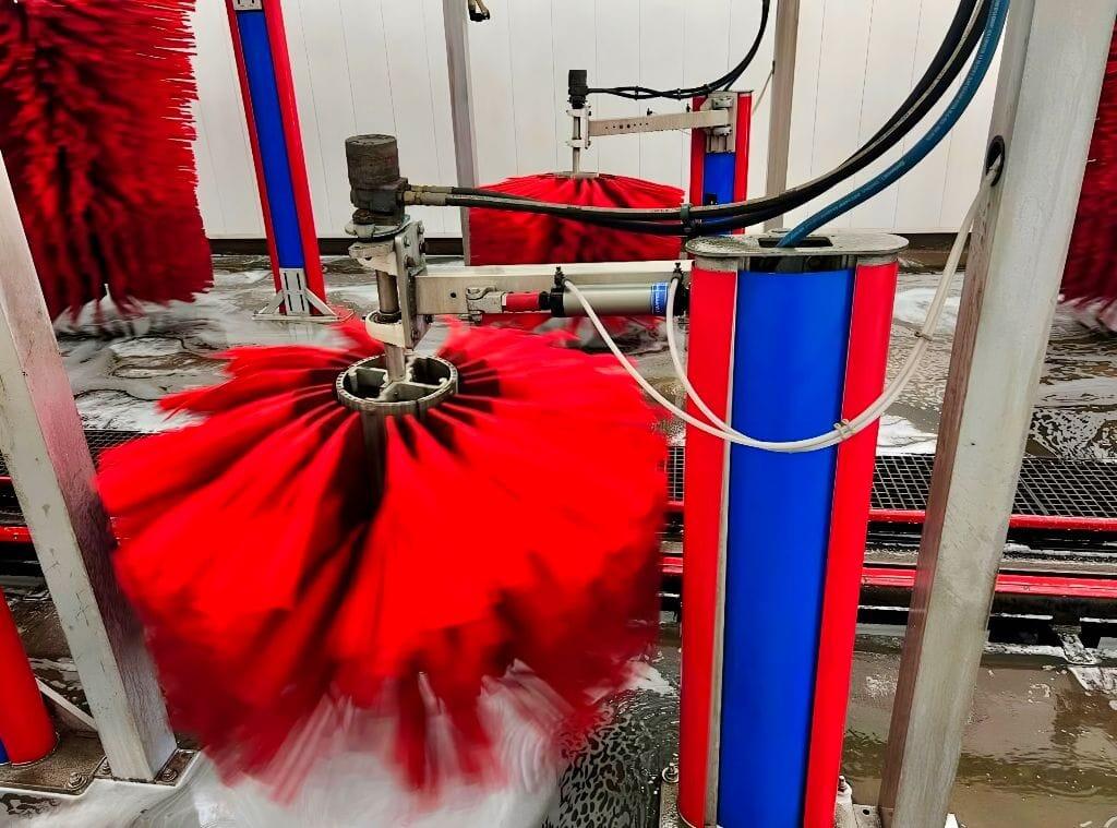 Brightworks Granbury exterior wash — close-up of a spinning red mitter brush in motion on the conveyor track