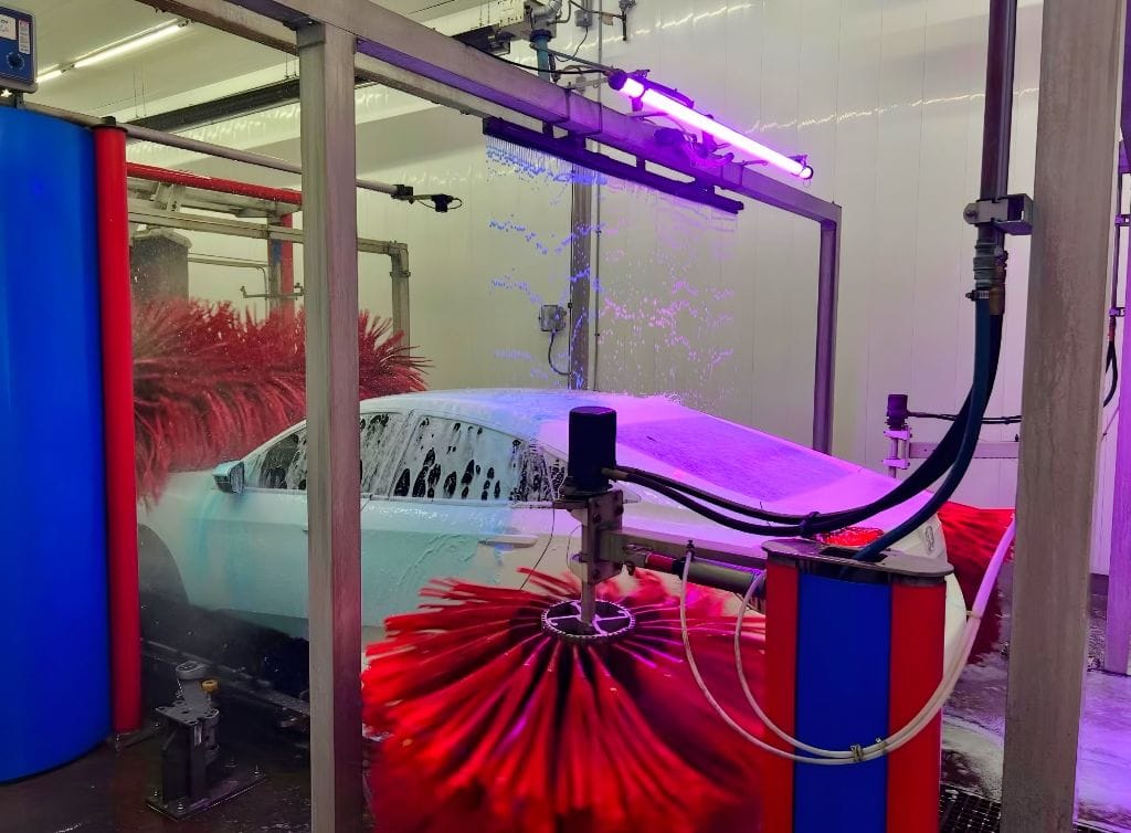 Brightworks Granbury express exterior wash — purple LED light show as soft-touch brushes wrap a white car in foam