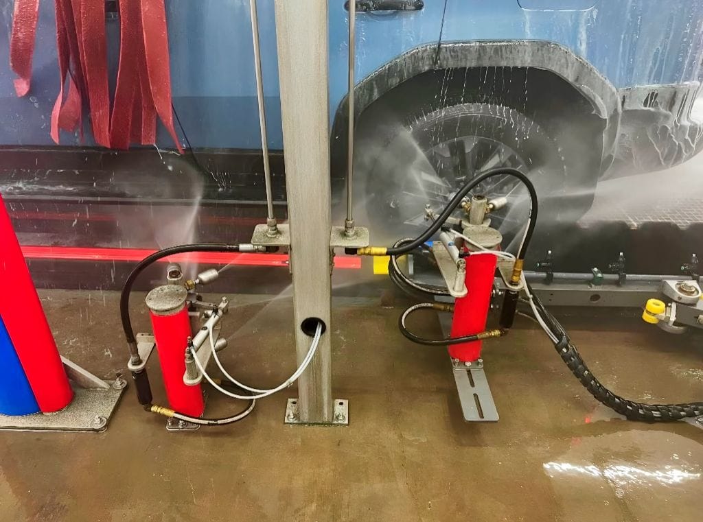 Brightworks Granbury exterior wash — under-carriage tire spray jets in action as a blue vehicle passes through